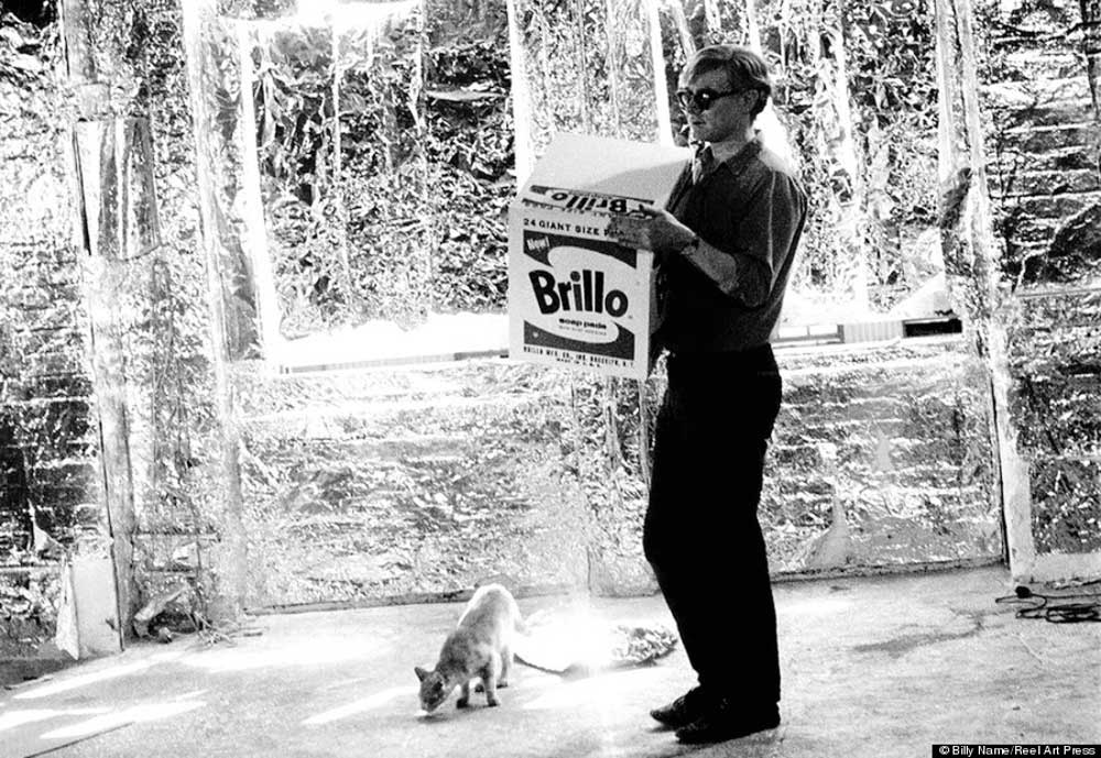 Andy Warhol con su obra Brillo